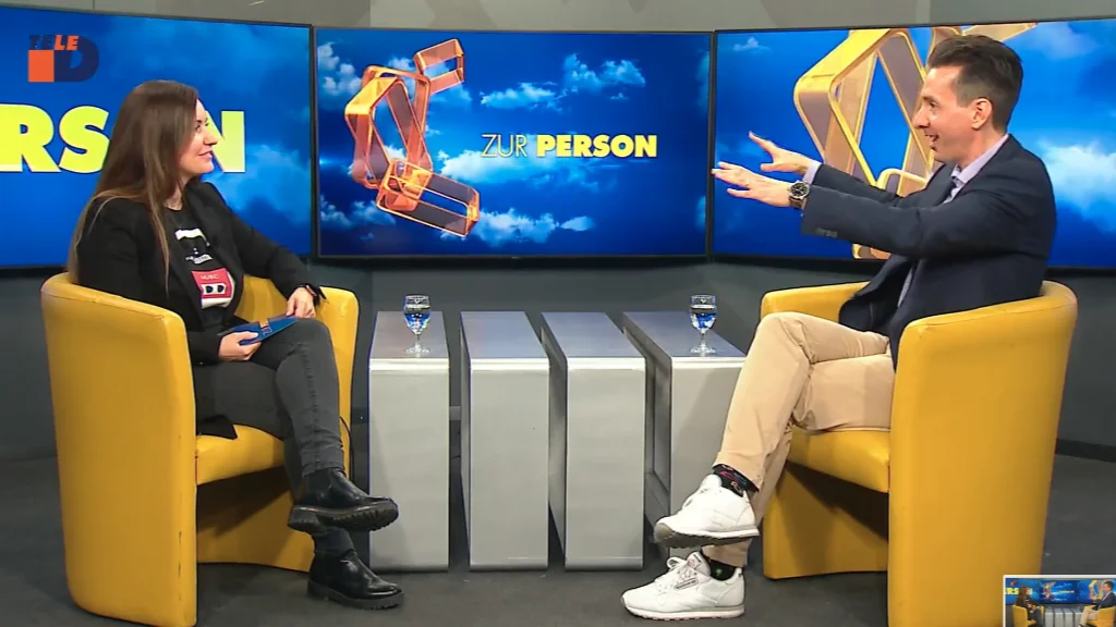 Two people sitting across from each other in a TV studio